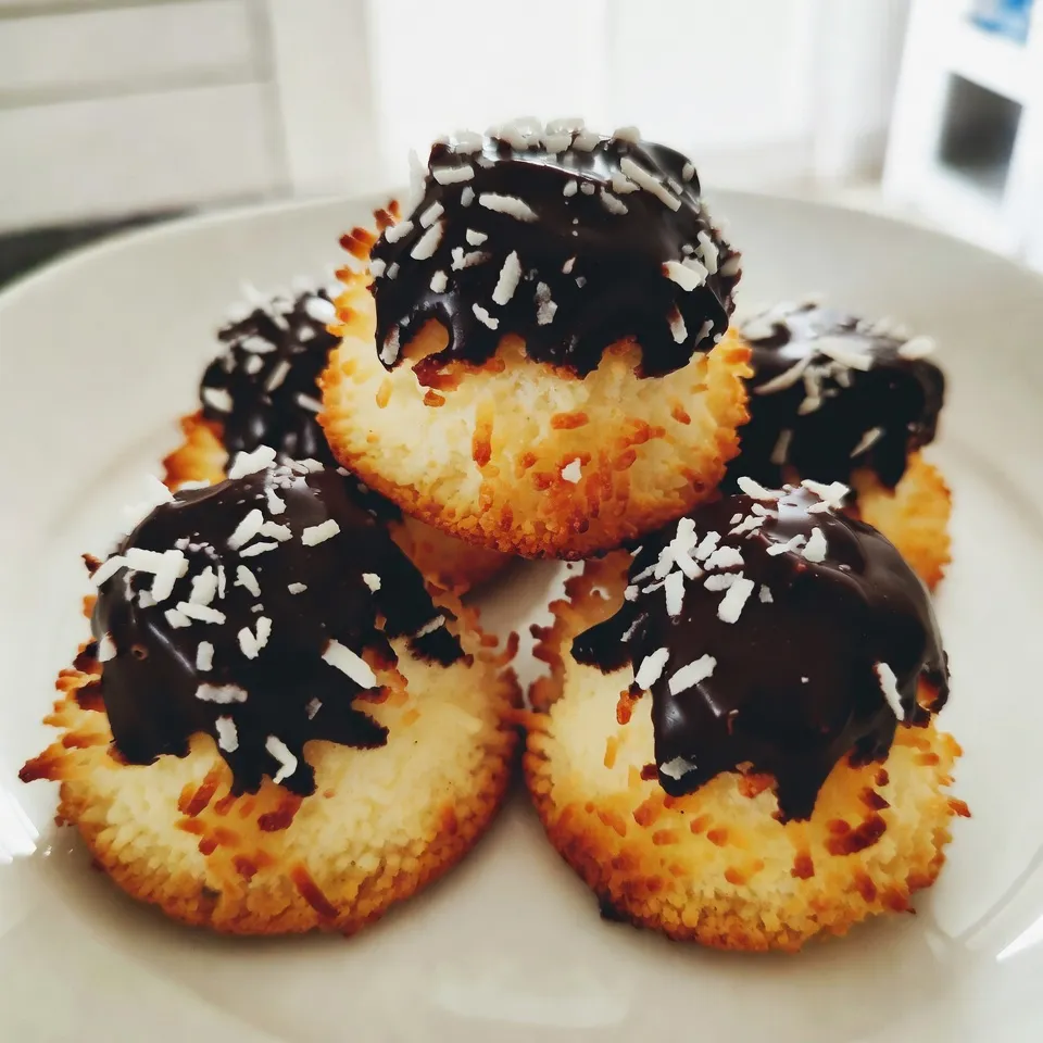 - 2 ½ cups shredded coconut (unsweetened) - 1 cup sweetened condensed milk - 1 teaspoon vanilla extract - ½ teaspoon almond extract - 1 cup semi-sweet chocolate chips - ¼ teaspoon sea salt - 2 large egg whites - 1 tablespoon coconut oil (for melting chocolate) Gather these ingredients before you start. Using unsweetened coconut helps balance the sweetness from the condensed milk. The vanilla and almond extracts add great flavor depth. The semi-sweet chocolate chips will give a rich finish to each macaroon. Keep the sea salt in mind; it enhances the sweet taste. Remember to use large egg whites for the right texture. Coconut oil helps the chocolate melt smoothly, making it easy to coat the macaroons. Each ingredient plays a role in creating this delightful treat. Enjoy the process of baking! {{ingredient_image_1}} 1. Preheat your oven to 325°F (160°C). Line a baking sheet with parchment paper. This helps the macaroons not stick. 2. In a large bowl, combine 2 ½ cups shredded coconut, 1 cup sweetened condensed milk, 1 teaspoon vanilla extract, ½ teaspoon almond extract, and ¼ teaspoon sea salt. Mix well until all ingredients blend together. 3. In a separate bowl, whip 2 large egg whites. Beat them until they form stiff peaks. This step makes your macaroons light and fluffy. 4. Gently fold the whipped egg whites into the coconut mixture. Be careful not to deflate the egg whites. Mix until just combined for the best texture. 5. Use a tablespoon or a small cookie scoop to form the mixture into mounds. Place them on the prepared baking sheet, leaving space between each macaroon. 6. Bake for 20-25 minutes. Look for golden brown tops. Once done, take them out and let them cool completely on the baking sheet. 1. To melt the chocolate, use 1 cup semi-sweet chocolate chips and 1 tablespoon coconut oil. Place them in a microwave-safe bowl. 2. Microwave in 30-second increments. Stir between each increment until smooth. This helps avoid burning the chocolate. 3. Once the macaroons are cool, dip the bottoms into the melted chocolate or drizzle chocolate over the tops. This adds a nice touch and flavor. 4. Place the dipped macaroons back on the parchment paper. Let the chocolate set at room temperature or in the fridge for quicker results. Enjoy your tasty treat! To make great macaroons, start by whipping the egg whites. Beat them until they form stiff peaks. This step adds lightness to your treats. Soft, fluffy macaroons come from well-whipped egg whites. Next, focus on folding. Gently add the whipped egg whites to the coconut mix. Use a spatula and fold carefully. This keeps the air in the egg whites. Do not stir too hard or too fast. You want to keep that airy texture for your macaroons. Baking time is key to avoid sticking. Line your baking sheet with parchment paper. This helps the macaroons lift off easily. Make sure they have space between them. They will spread a bit while baking. Look for the signs of doneness. The tops should turn golden brown. If they are too light, they may be undercooked. Allow them to cool on the sheet. This helps them set and stay firm. Pro Tips Use Fresh Coconut: For an even richer flavor, try using fresh shredded coconut instead of dried. It will enhance the texture and taste of your macaroons. Perfect Egg Whites: Ensure your mixing bowl is free of any grease before whipping the egg whites. This will help them achieve maximum volume and stability. Chocolate Tempering: If you want a glossy finish on your chocolate, consider tempering it before dipping. This gives a professional touch and helps the chocolate set better. Storage Tips: Keep macaroons in an airtight container at room temperature for up to a week. For longer storage, refrigerate them to maintain freshness. {{image_2}} You can easily change the flavor of your chocolate coconut macaroons. Adding spices like cinnamon or nutmeg can give them a warm twist. Just a pinch of either spice works wonders. If you want a richer taste, mix in some chocolate chunks or nuts. Chopped almonds or pecans add a nice crunch and depth. Coating your macaroons can enhance their look and flavor. You can dip them in white or dark chocolate for a sweet touch. Each type of chocolate brings a different taste. For a fun finish, try decorating with toppings. Crushed nuts or colorful sprinkles make your treats pop. They become more festive and inviting this way. To keep your chocolate coconut macaroons fresh, choose the right container. An airtight container works best. This keeps moisture out and flavor in. Glass or plastic containers both work well. Store your macaroons at room temperature for short-term use. They stay fresh for a few days this way. If you live in a warm area, consider refrigeration. It helps them stay firm and cool. Chocolate coconut macaroons last about one week at room temperature. If you want to save them longer, freezing is a great option. Wrap each macaroon in plastic wrap. Then, place them in a freezer bag. This method keeps them tasty for up to three months. When you're ready to enjoy, let them thaw at room temperature. No need to rush, as they taste great even after freezing! What are the differences between macaroons and macarons? Macaroons and macarons are not the same. Macaroons are made with coconut and are chewy. They often have a sweet taste. Macarons are French cookies made from almond flour. They are light, airy, and have fillings. Each has its charm, but they are quite different in taste and texture. Can I use sweetened coconut instead of unsweetened? Yes, you can use sweetened coconut. It will make your macaroons sweeter. If you prefer less sweetness, stick with unsweetened coconut. Adjust the sugar in your recipe if needed. This choice adds a fun twist to your treats. Is there a vegan option for these macaroons? Yes! You can make vegan macaroons. Replace the egg whites with aquafaba. Aquafaba is the liquid from canned chickpeas. It works well for whipping. Use the same amount as the egg whites. Your macaroons will still be tasty and fluffy. Why are my macaroons too dry or too wet? If your macaroons are too dry, you may not have enough moisture. Make sure to use enough sweetened condensed milk. If they are too wet, try adding a bit more coconut. Adjusting these ingredients helps get the right texture. How can I fix macaroons that spread too much? If your macaroons spread too much, check your oven temperature. Make sure it’s at 325°F (160°C). If it’s too low, your macaroons will spread. Also, try chilling the dough for 15 minutes before baking. This can help them keep their shape. You now have a clear path to make delicious macaroons. We covered key ingredients, step-by-step methods, tips for perfect texture, and ways to customize your flavor. Proper storage and answers to common questions help you succeed. Baking can be fun and rewarding. Keep experimenting with flavors and techniques. Enjoy the process, and you’ll create treats loved by many. Happy baking!